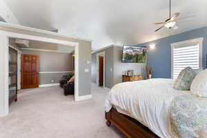 Carpeted bedroom featuring ceiling fan, vaulted ceiling, and ornamental molding