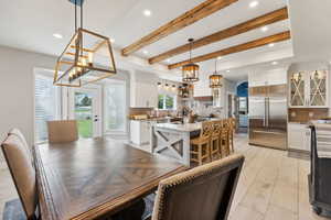 Dining room featuring beam ceiling, a healthy amount of sunlight, and a notable chandelier