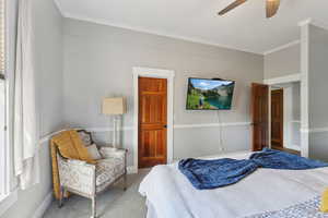 Bedroom with ceiling fan, carpet floors, and crown molding