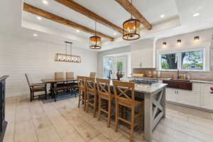 Kitchen featuring white cabinets, a center island, decorative light fixtures, and sink