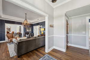 Living room featuring french doors, dark hardwood / wood-style floors, an inviting chandelier, and crown molding