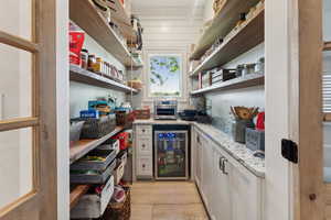 Interior space with light stone countertops, white cabinetry, and beverage cooler