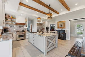 Kitchen featuring a center island with sink, premium appliances, and white cabinets