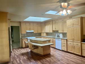 Kitchen featuring hardwood / wood-style floors, a center island, white dishwasher, and sink