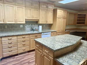 Kitchen with dishwasher, sink, tasteful backsplash, light hardwood / wood-style floors, and light brown cabinetry