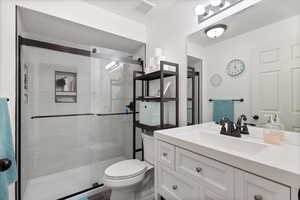 Bathroom with vanity, toilet, and a shower with door