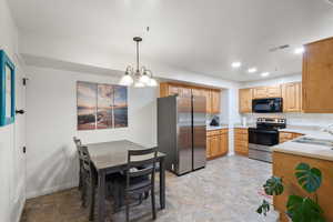 Kitchen featuring a chandelier, hanging light fixtures, stainless steel appliances, and sink