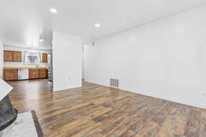 Unfurnished living room featuring sink and dark wood-type flooring