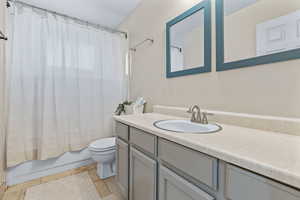 Full bathroom featuring shower / bath combo with shower curtain, tile patterned flooring, vanity, and toilet