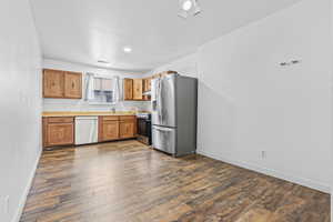 Kitchen with stainless steel appliances, dark wood-type flooring, and range hood