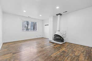 Unfurnished living room featuring dark hardwood / wood-style floors and a wood stove