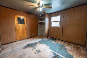 Bedroom #3 featuring ceiling fan, wooden walls, and light hardwood / wood-style floors