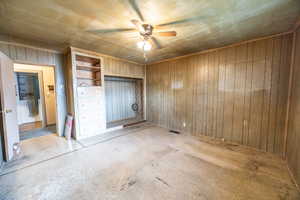 Bedroom #1 with a closet, ceiling fan, and wood walls