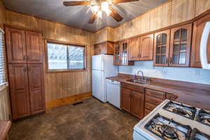 Kitchen featuring sink, white appliances, and wood walls