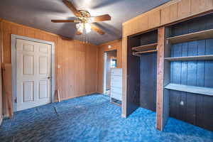 Bedroom #2 featuring ceiling fan, wooden walls, a textured ceiling, and dark colored carpet