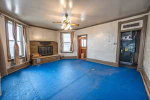 Unfurnished living room featuring crown molding, a fireplace, and ceiling fan