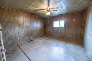 Bedroom #1featuring ceiling fan and wood walls