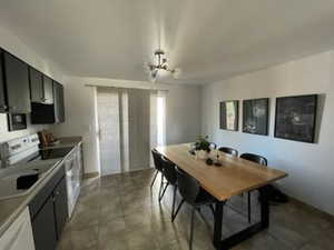 Kitchen featuring an inviting chandelier, white range with electric cooktop, plenty of natural light, and dark tile patterned flooring