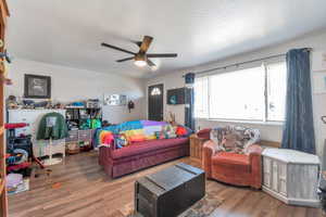 Living room with a textured ceiling, ceiling fan, and dark hardwood / wood-style floors