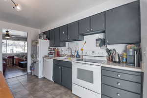 Kitchen with ceiling fan, light tile patterned floors, sink, and white appliances