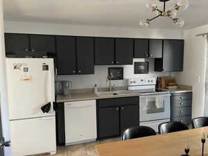 Kitchen with light tile patterned flooring, sink, and white appliances