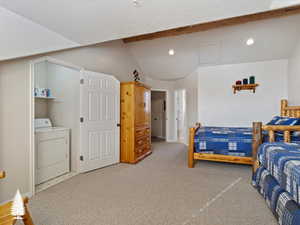 Carpeted bedroom with lofted ceiling with beams, a textured ceiling, and washer / clothes dryer