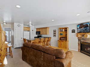 Living room featuring a stone fireplace and light carpet