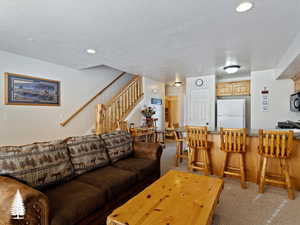 Living room featuring carpet flooring, sink, and a textured ceiling