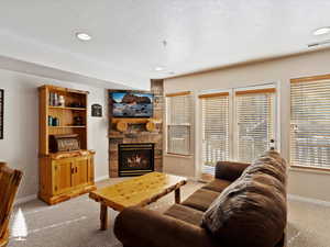 Carpeted living room featuring a fireplace and a textured ceiling