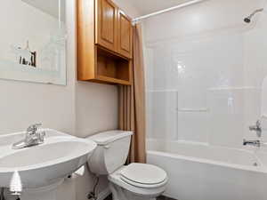 Full bathroom featuring sink, shower / bathtub combination with curtain, and toilet