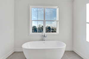 Bathroom with tile patterned floors and a tub to relax in