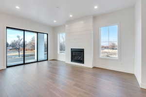 Unfurnished living room featuring hardwood / wood-style floors, a large fireplace, and a wealth of natural light