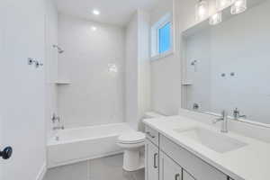 Full bathroom with tile patterned floors, vanity, toilet, and tiled shower / bath