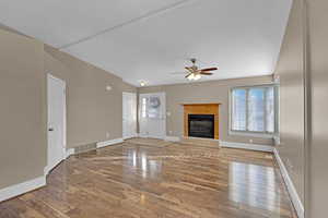 Freshly painted living room featuring laminate flooring, ceiling fan, and a tiled fireplace