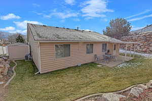 Rear view of property featuring a lawn, a storage unit, a patio area, and central air condition unit