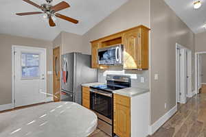 Kitchen with ceiling fan, backsplash, wood-type flooring, lofted ceiling, and appliances with stainless steel finishes