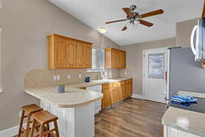 Kitchen featuring  dishwasher, a kitchen breakfast bar, sink, vaulted ceiling, and kitchen peninsula