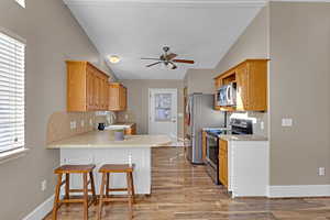 Kitchen with backsplash, a breakfast bar, stainless steel appliances, sink, and lofted ceiling