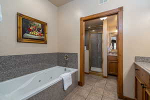 Bathroom with vanity, tile patterned floors, and independent shower and bath