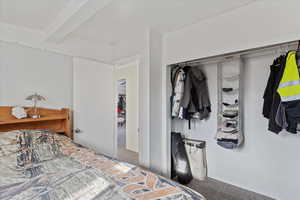 Bedroom with beamed ceiling and carpet floors