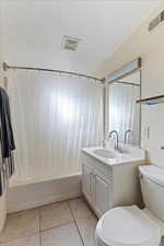 Full bathroom with tile patterned floors, vanity, shower / bathtub combination with curtain, and toilet