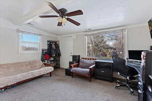 Carpeted office featuring a textured ceiling, lofted ceiling with beams, and ceiling fan