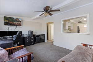 Interior space with beam ceiling, ceiling fan, sink, a textured ceiling, and carpet