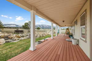 Wooden terrace featuring a mountain view, covered porch, and a lawn