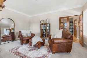 Living room with french doors, light colored carpet, and ornamental molding