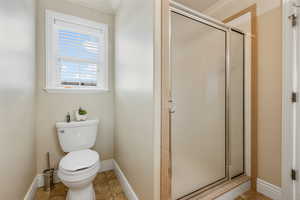 Bathroom featuring toilet, an enclosed shower, and ornamental molding