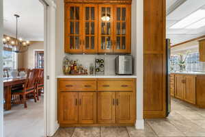 Bar featuring light carpet, decorative light fixtures, a chandelier, and crown molding