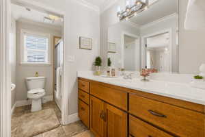 Bathroom with toilet, vanity, ornamental molding, and walk in shower