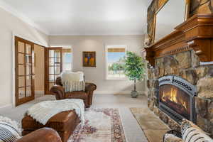 Carpeted living room with a fireplace, french doors, and crown molding