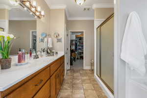 Bathroom with tile patterned floors, vanity, an enclosed shower, and crown molding